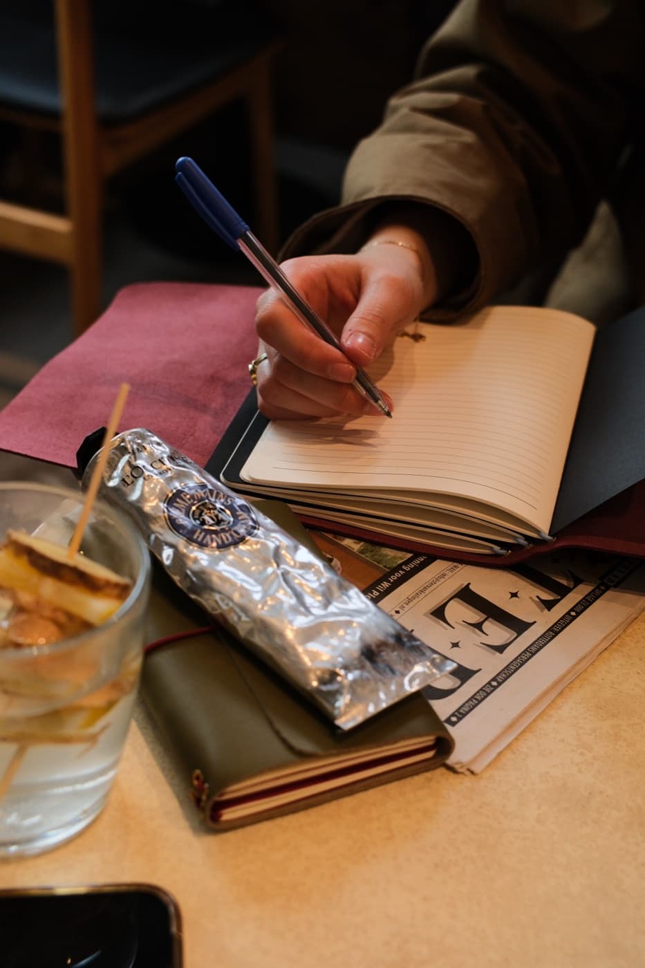 Schrijven in een nieuwe journal aan een cafétafel, omringd door boeken